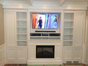 White shelvings around a TV set and fireplace